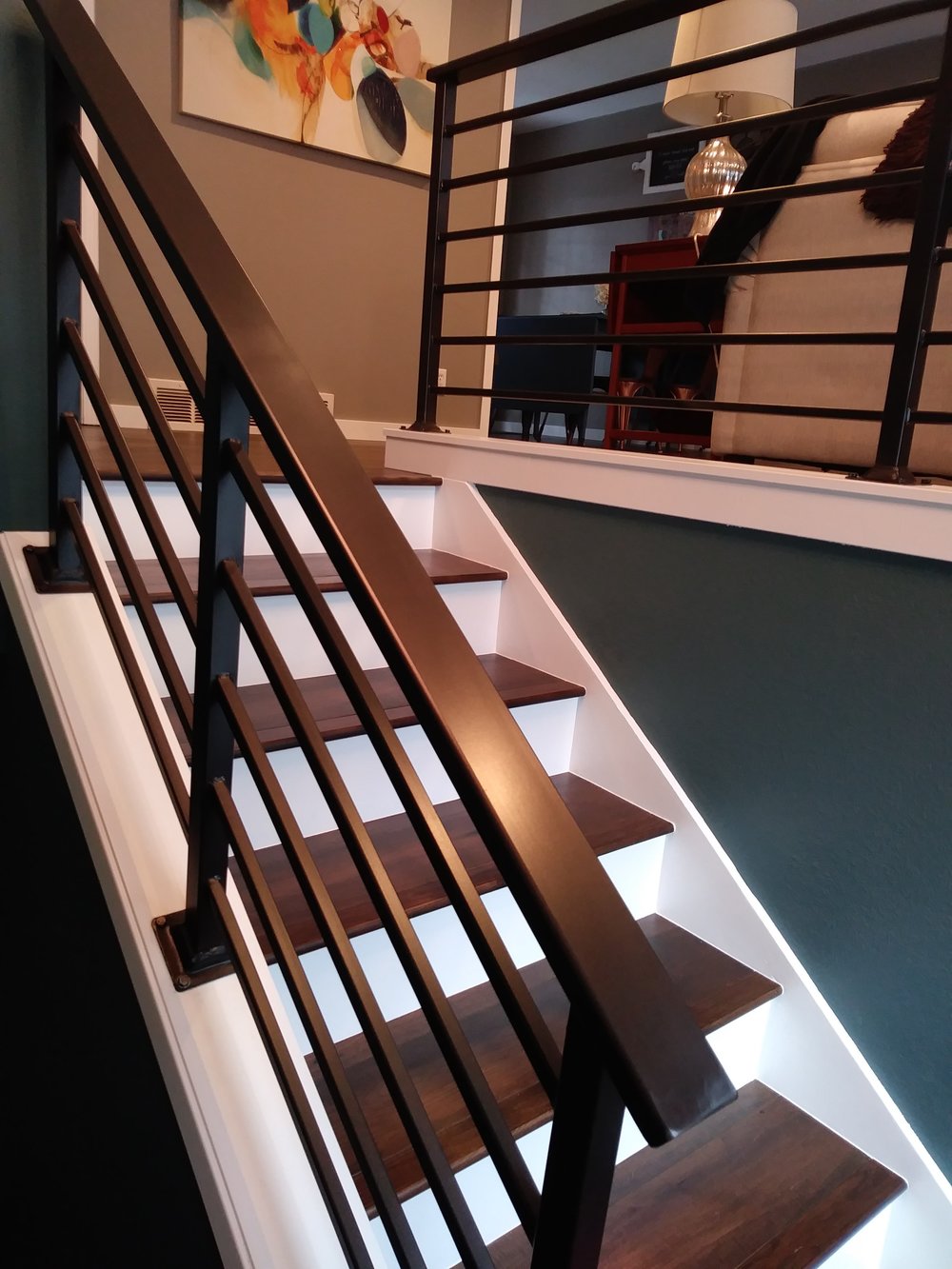 Custom interior staircase with dark wood treads and a black metal railing built by Emmanuel Construction