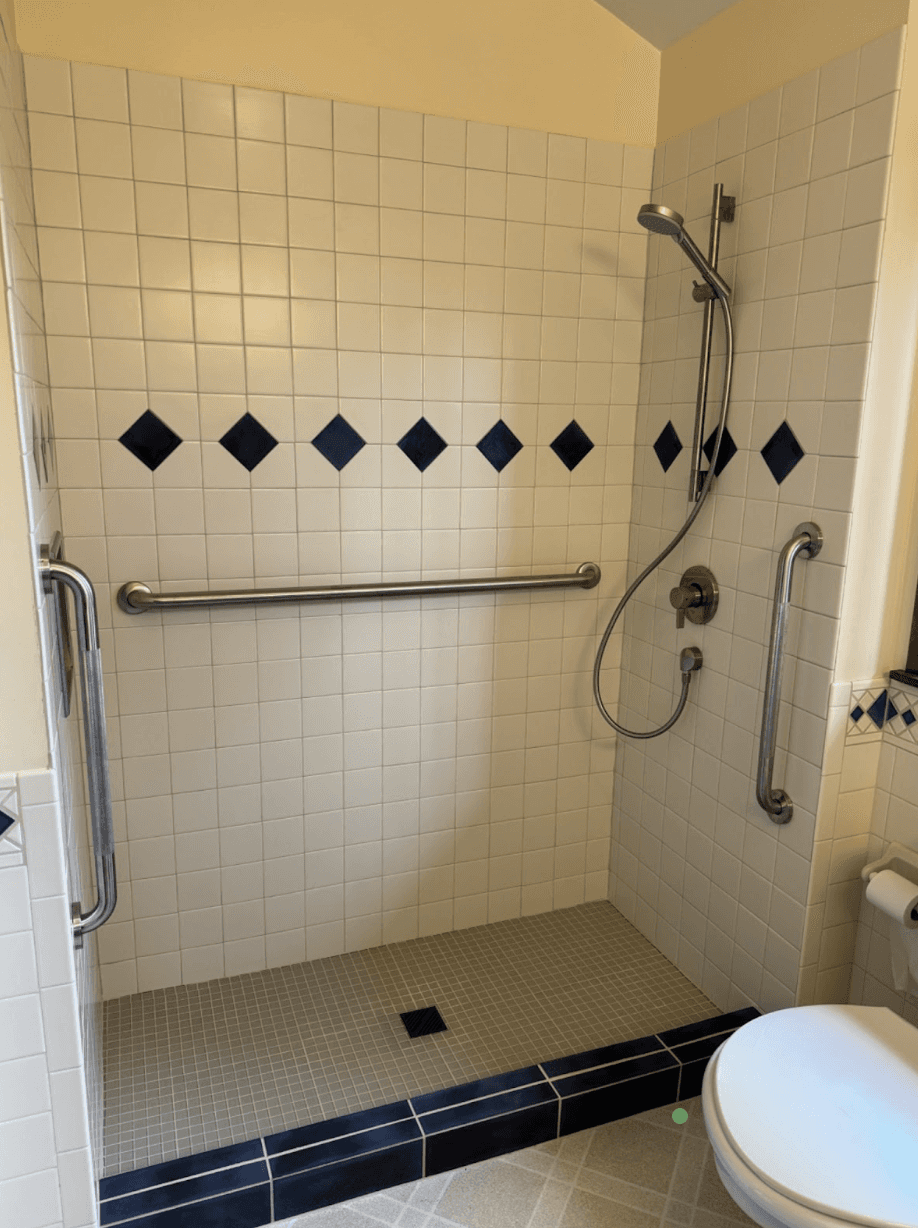 Walk-in shower conversion with tiled walls, grab bars and a handheld shower head replacing an old tub